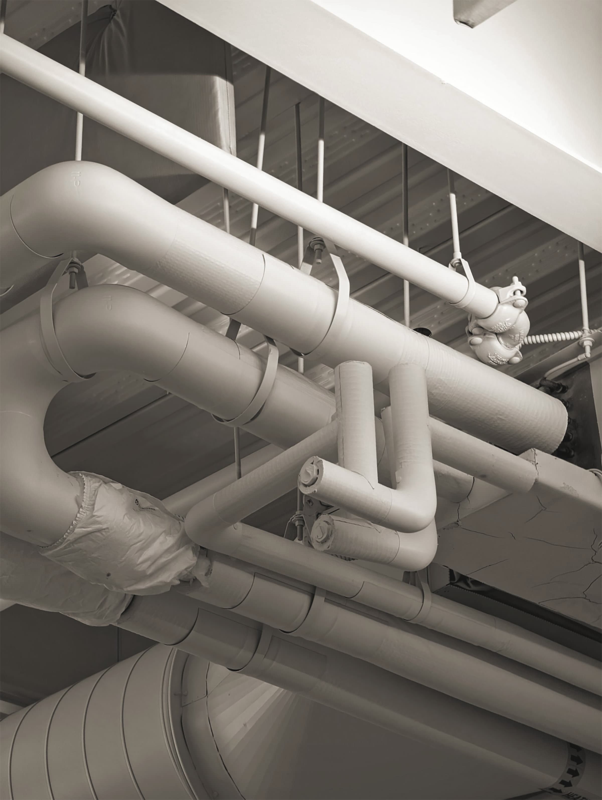 Flat oval ductwork and VAV boxes photographed looking up into a shallow ceiling void